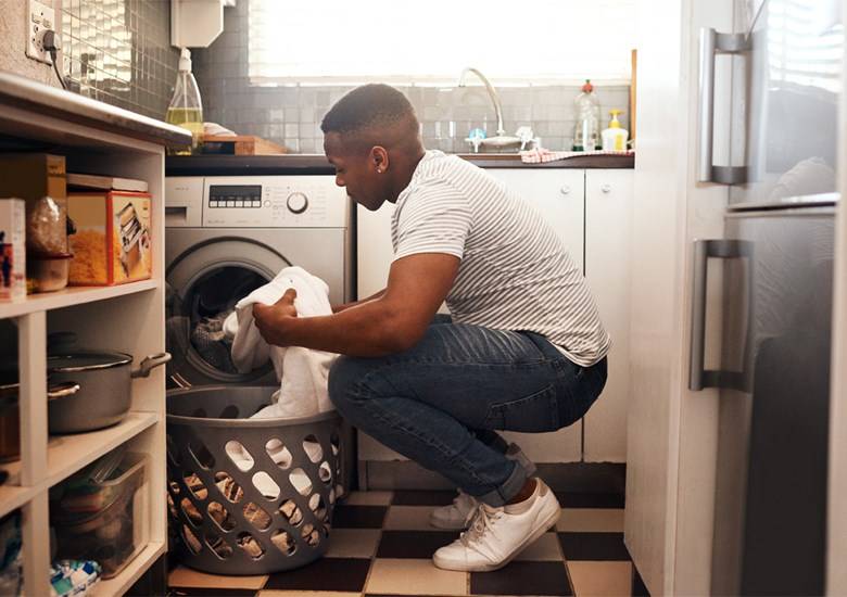 Hombre agarrando camisa blanca frente a una secadora